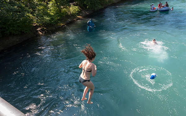 Frau im Badeanzug springt von einer Brücke in den Fluss Aare.