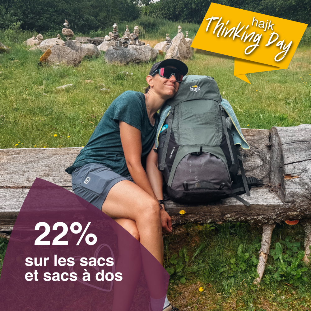 Gros plan d'une jeune femme en tenue de randonnée se blottissant contre son sac à dos de trekking sur un banc en bois.