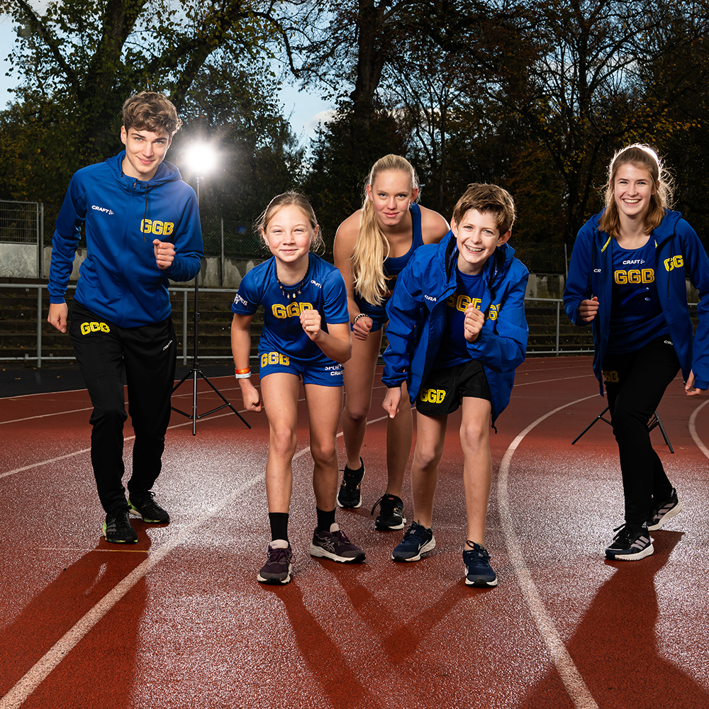 Gruppe Jugendlicher posieren in Teambekleidung auf einer Tartanbahn in der Nacht.