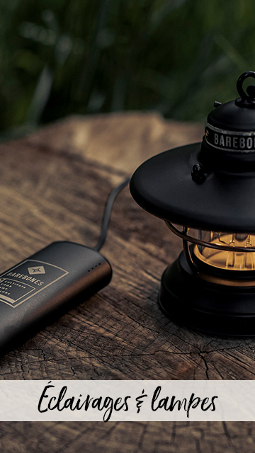 Gros plan sur une lanterne Barebones sur une table en bois, en train de se recharger avec un chargeur.