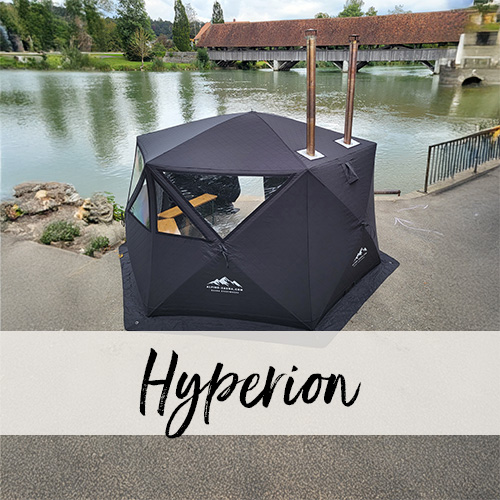 Sauzanzelt Hyperion Saunazelt Hyperion steht auf einem asphaltierten Parkplatz neben einem Fluss. Im Hintergrund ist eine gedeckte Holzbrücke zu sehen.