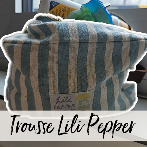 Gros plan d’une trousse de toilette rayée, bien remplie, posée sur un rebord de fenêtre dans une salle de bain.