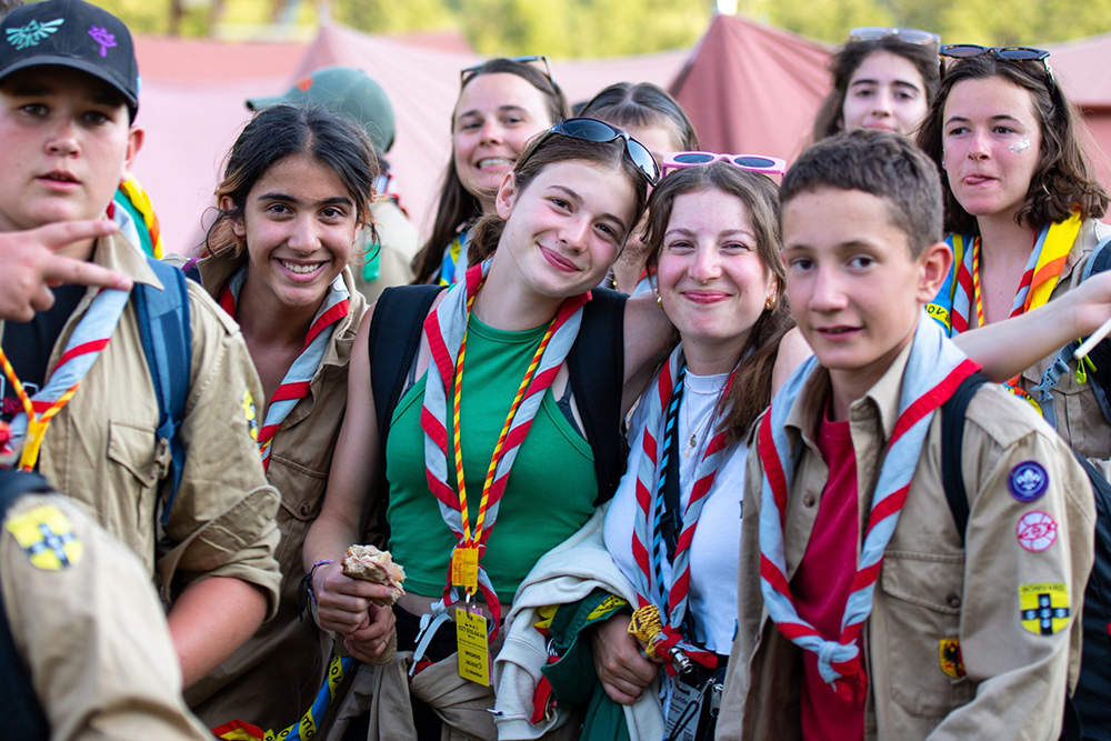 Une troupe de scouts et guides en tenue, souriants et fiers, prêts pour l’aventure.