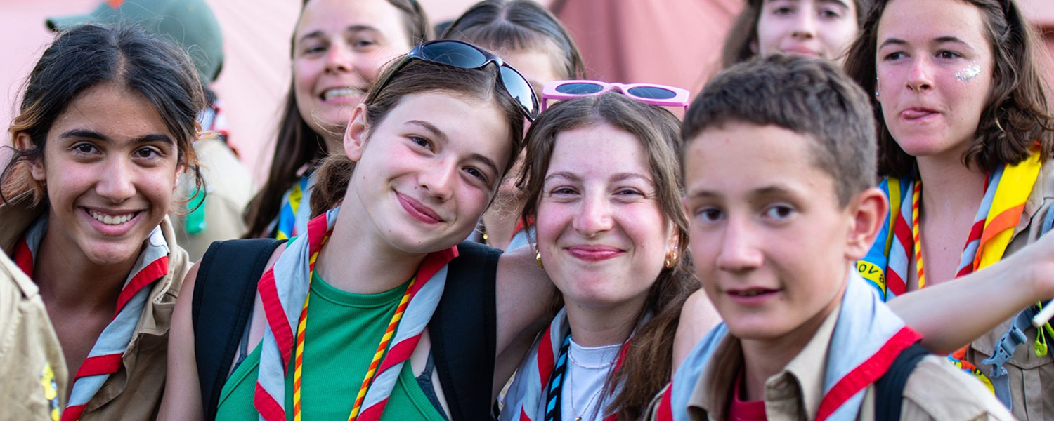 Une troupe de scouts et guides en tenue, souriants et fiers, prêts pour l’aventure.